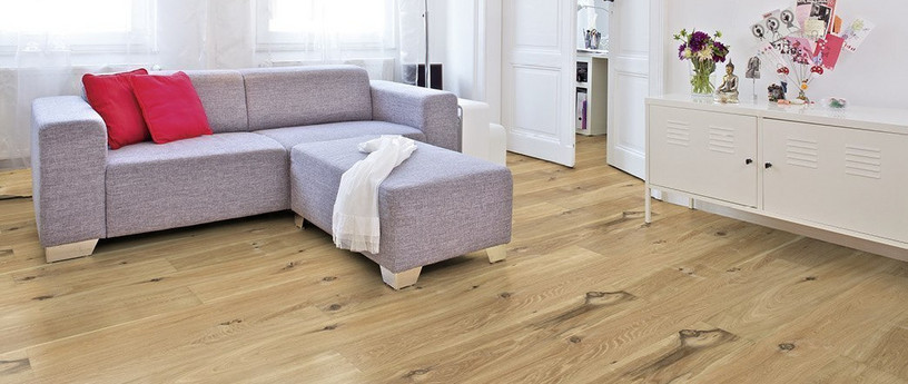 Im Wohnzimmer ist Parkett in Langdielen-Optik verlegt. Dazu passt ein Ecksofa mit bunten Kissen.