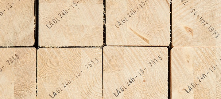 Gestapelte Brettschichtholzbalken mit sichtbarer Jahresringstruktur und Markierungen für den Holzbau.