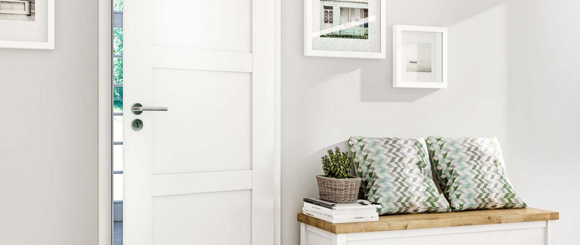 Weiße Innentür mit Edelstahlgriff, teilweise geöffnet, mit Blick auf Garten im Hintergrund.