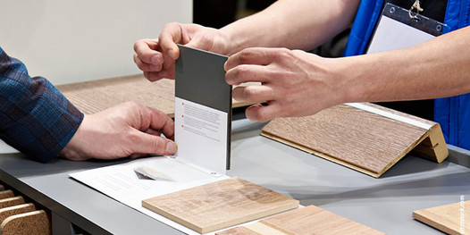 Kundenberatung im Fachhandel: Zwei Personen begutachten verschiedene Materialmuster für Bodenbeläge.