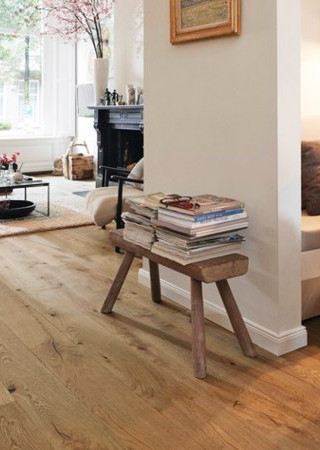 Wohnzimmer mit hellem Eichenparkett, schlichter Holzbank und gemütlicher Einrichtung.