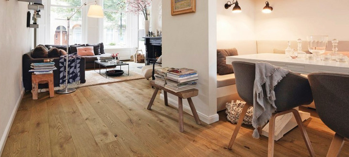 Wohnzimmer mit hellem Eichenparkett, schlichter Holzbank und gemütlicher Einrichtung.