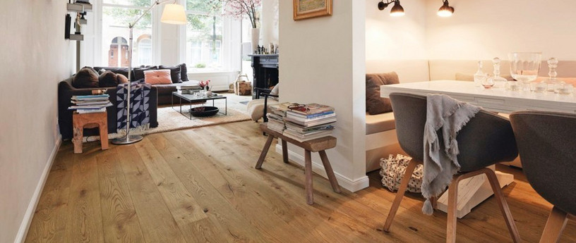 Wohnzimmer mit hellem Eichenparkett, schlichter Holzbank und gemütlicher Einrichtung.