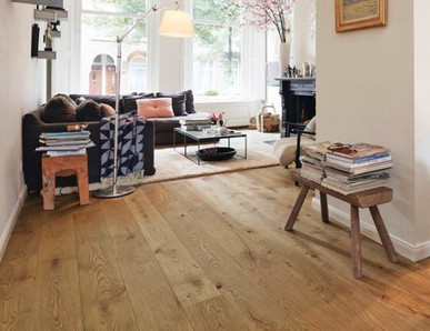 Wohnzimmer mit hellem Eichenparkett, schlichter Holzbank und gemütlicher Einrichtung.