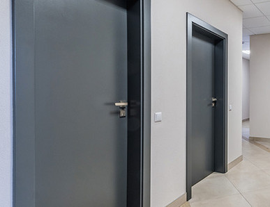 Mehrere anthrazitfarbene Wohnungstüren, Blick vom Treppenhaus.