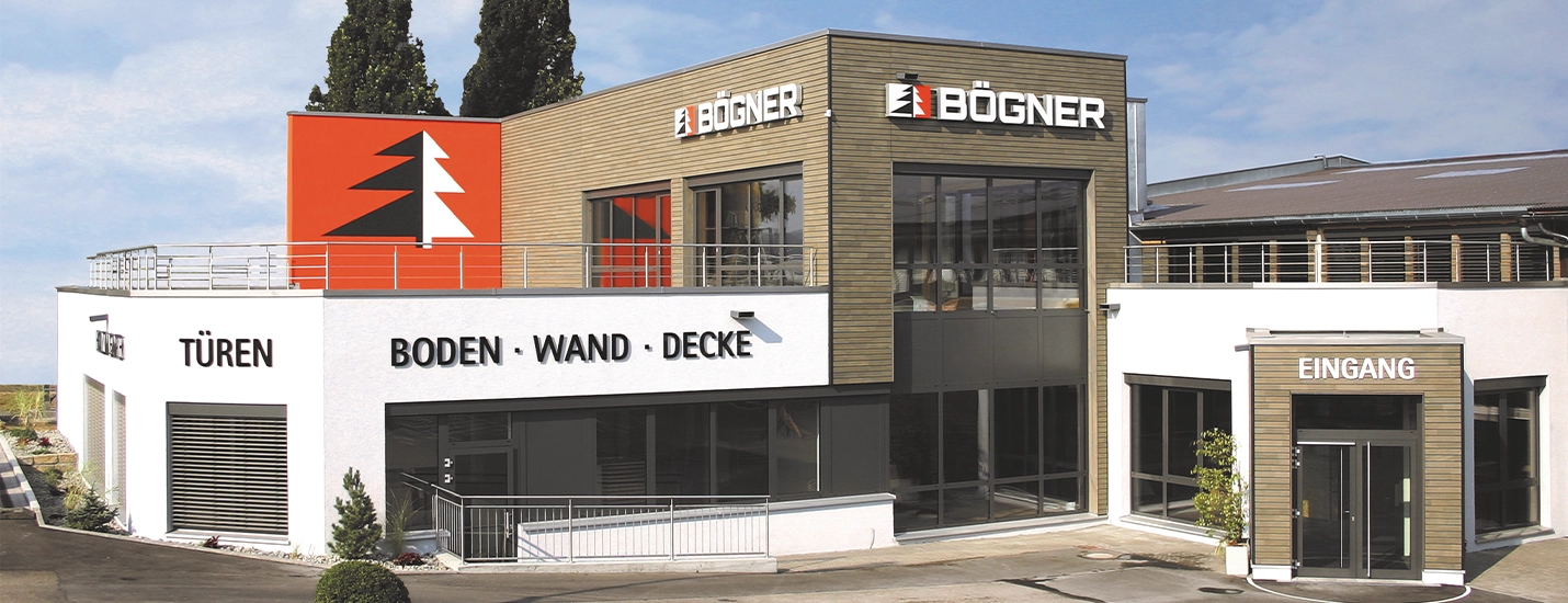 Modernes Holz Bögner Firmengebäude mit Eingangsbereich, Firmenlogo und großzügigen Ausstellungsflächen für Holz und Baustoffe.